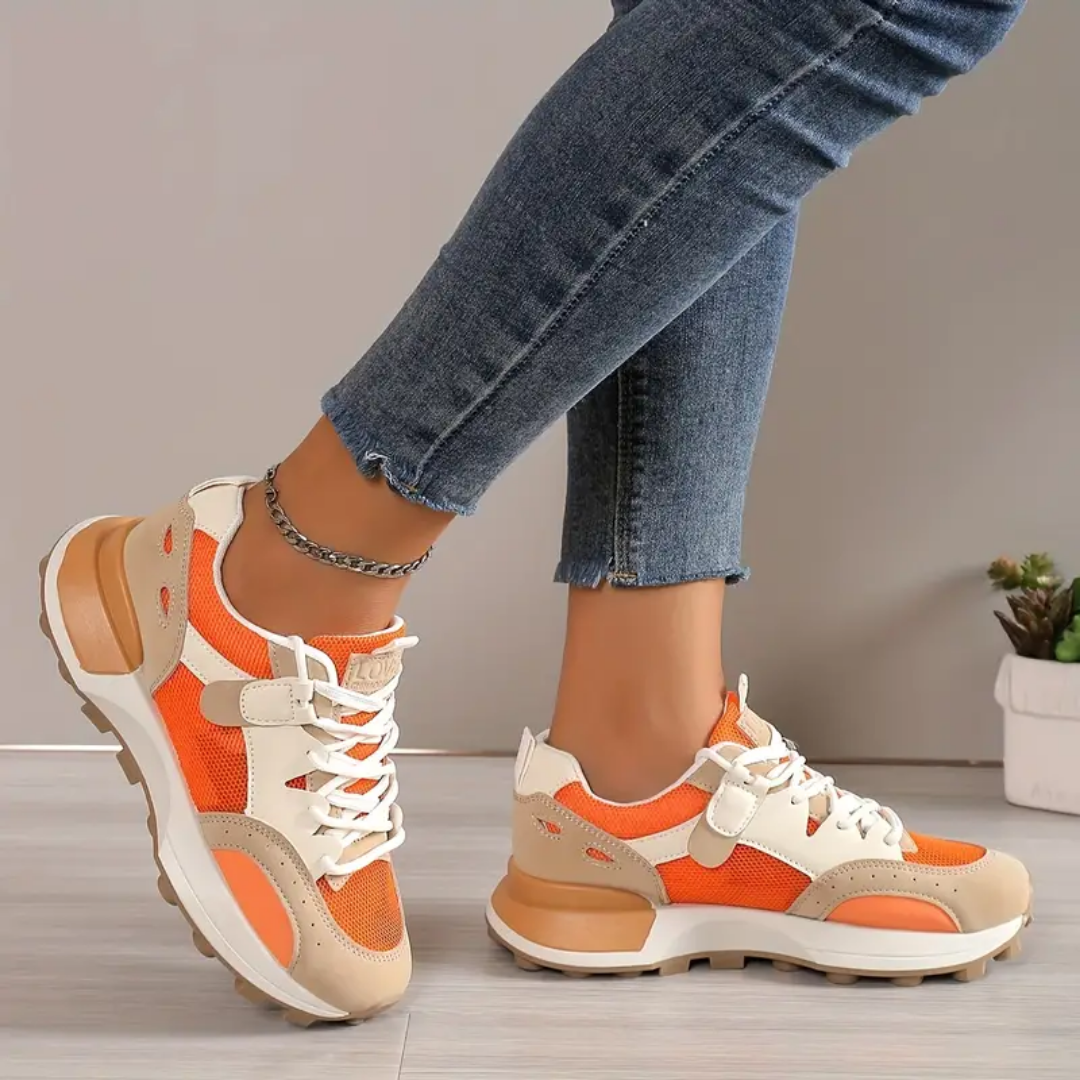 Model draagt stijlvolle modieuze orthopedische sneakers voor dames ondersteunende schoenen met elastiche sluiting oranje beige wit