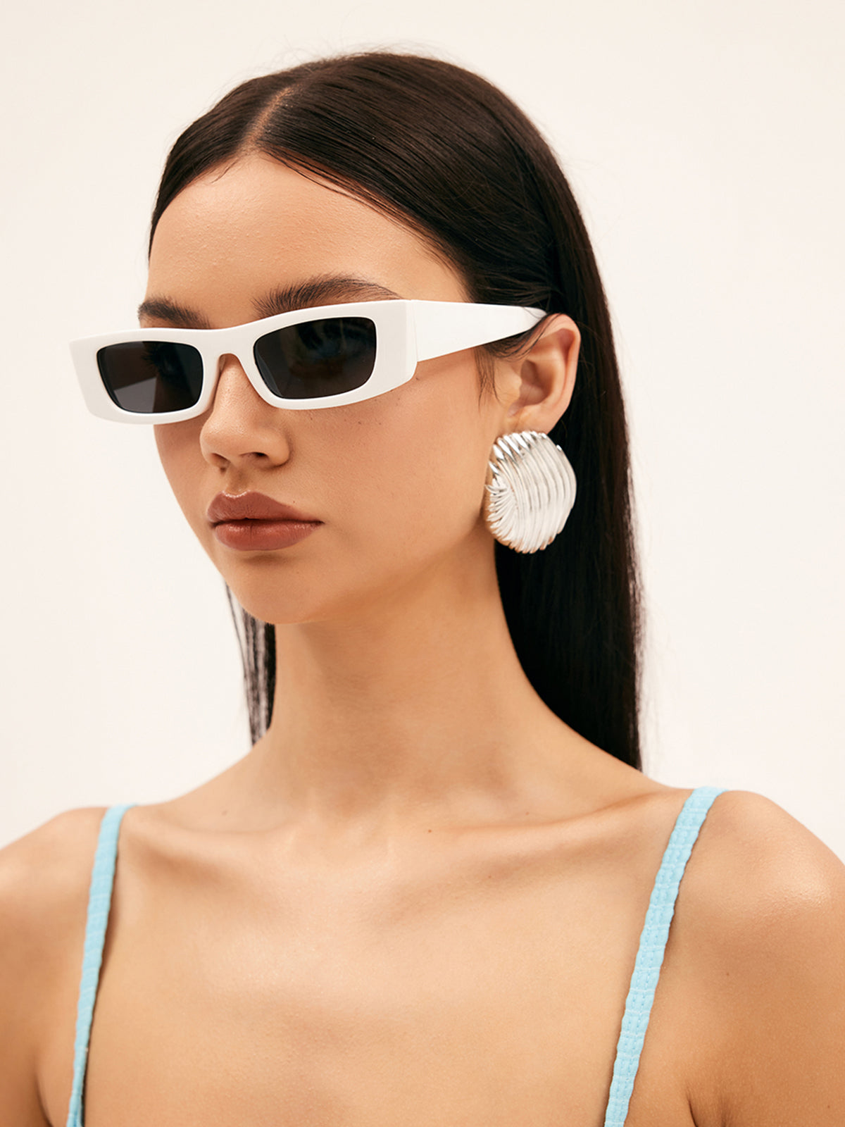 Model draagt zonnebril met vierkant montuur rechthoek montuur voor dames zomer festival bril modieus uv wit met donkere glazen