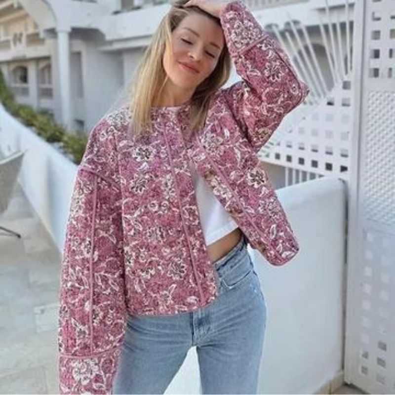 Deze stijlvolle zomerjas combineert de warmte van gewatteerde stof met een levendige bloemenprint, perfect voor koelere zomerdagen en -avonden.