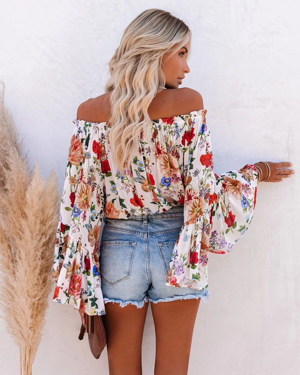 De unieke one-shoulder stijl en levendige bloemenprint maken deze blouse een echte eyecatcher voor elke zomerse gelegenheid.