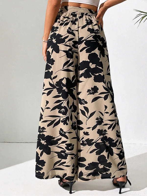 Model draagt wijde broek met bloemenprint en hoge taille losse broek linnen katoenen zomer broek dames met witte top striksluiting taille sluiting beige zwart