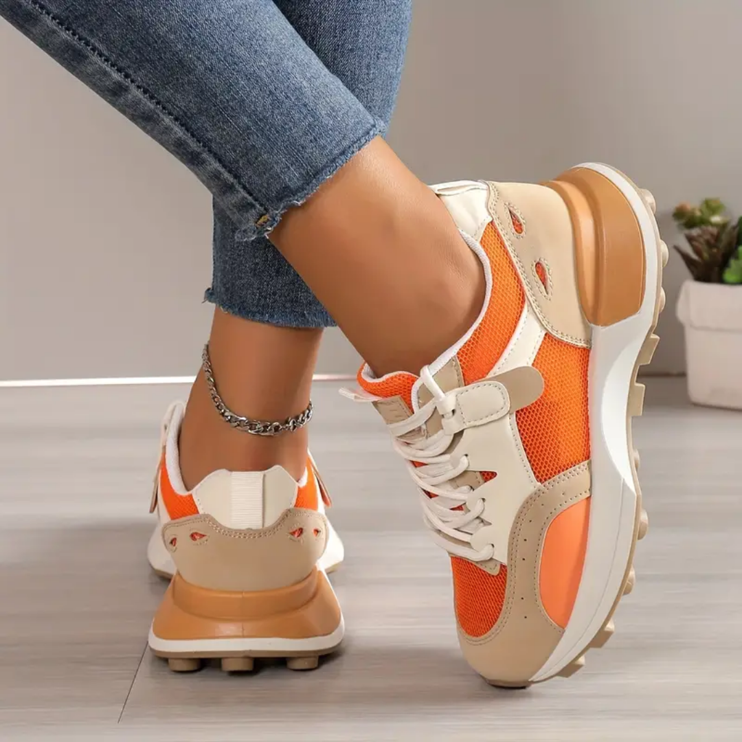 Model draagt stijlvolle modieuze orthopedische sneakers voor dames ondersteunende schoenen met elastiche sluiting oranje beige wit