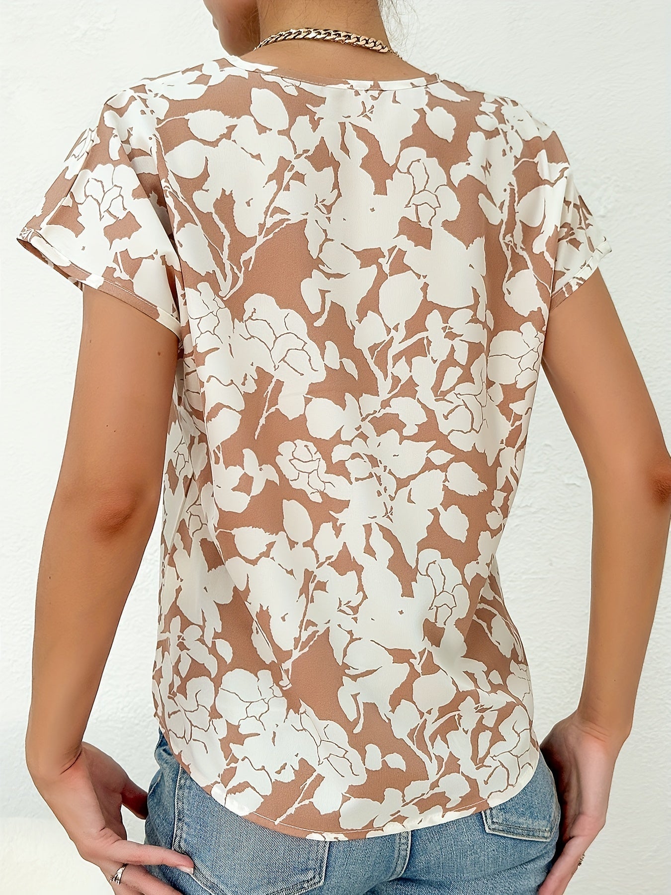 Model draagt zomer blouse met diep V-hals dames top met korte mouwen en bloemenprint beige