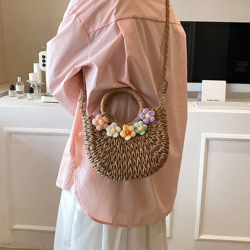 Deze charmante tas combineert de natuurlijke textuur van riet met kleurrijke bloemenaccenten, perfect voor het toevoegen van een vrolijke en elegante touch aan elke zomerse outfit.