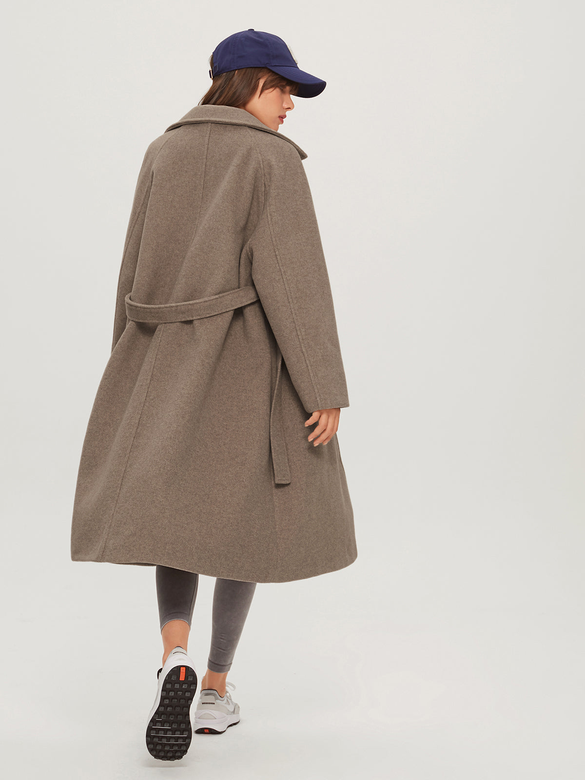 Model draagt lange cashmere trenchcoat voorjaarsjas met knoopsluiting voor en lange riem belt khaki beige