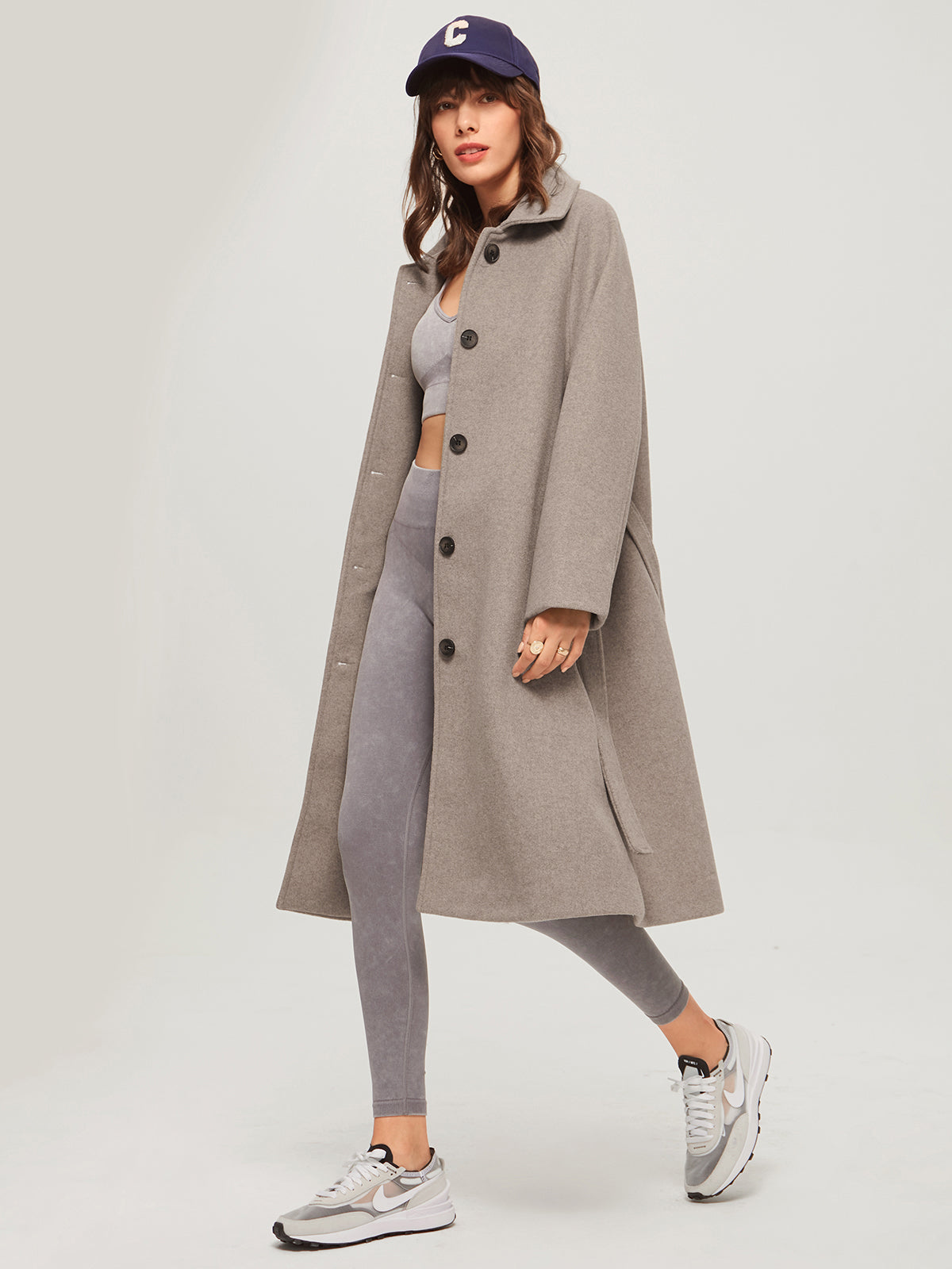 Model draagt lange cashmere trenchcoat voorjaarsjas met knoopsluiting voor en lange riem belt khaki beige