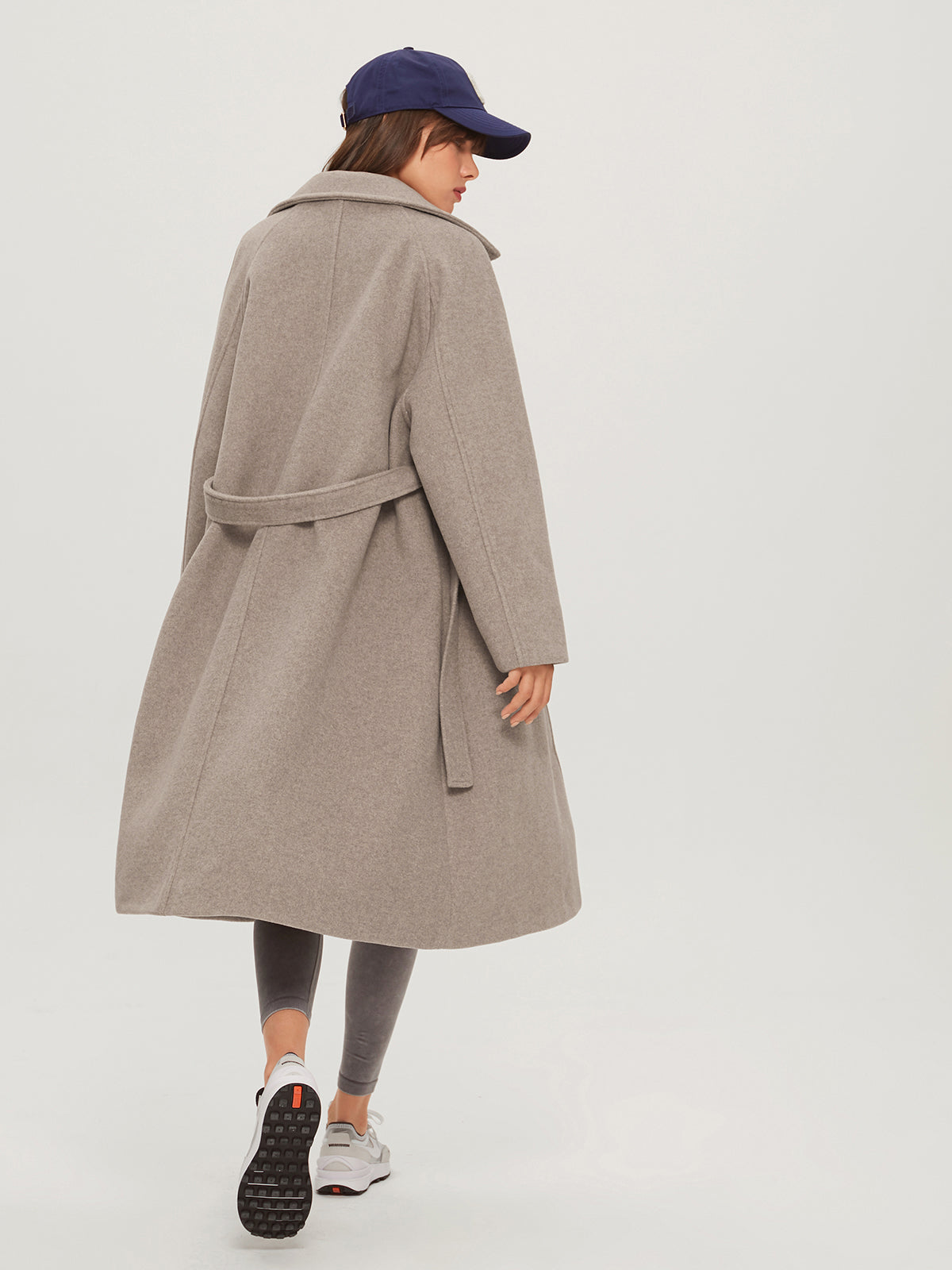 Model draagt lange cashmere trenchcoat voorjaarsjas met knoopsluiting voor en lange riem belt khaki beige