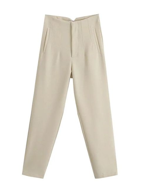 Model draagt chique damesbroek met hoge taille, pakbroek broekpak dames met gevouwen details bij de heupen en broekzakken, broek heeft wijde pijpe met een dunne stof, zomerbroek linnen broek vrouwen beige