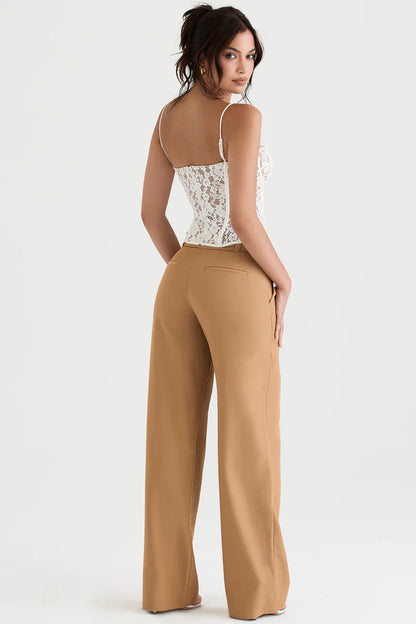 Model draagt Caramel kleurige pantalon wijde pijp knoopsluiting met wit kanten beugel korset broekpak