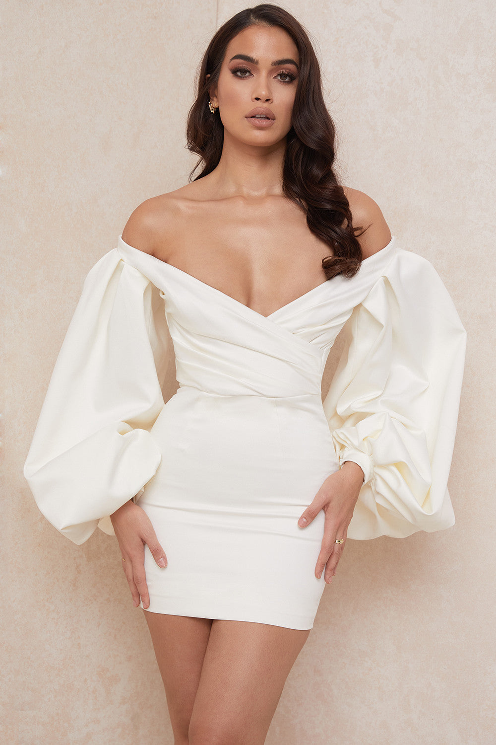 De gladde satijnen stof zorgt voor een luxueuze uitstraling, terwijl de off shoulder snit en dramatische ballonmouwen een vleugje romantiek en allure toevoegen aan je look.