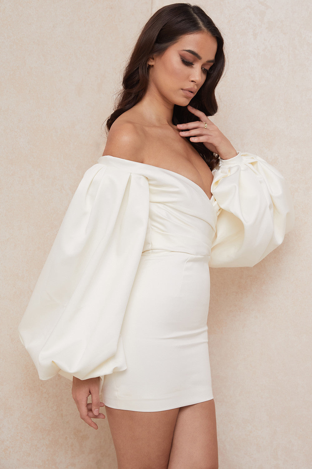 De gladde satijnen stof zorgt voor een luxueuze uitstraling, terwijl de off shoulder snit en dramatische ballonmouwen een vleugje romantiek en allure toevoegen aan je look.