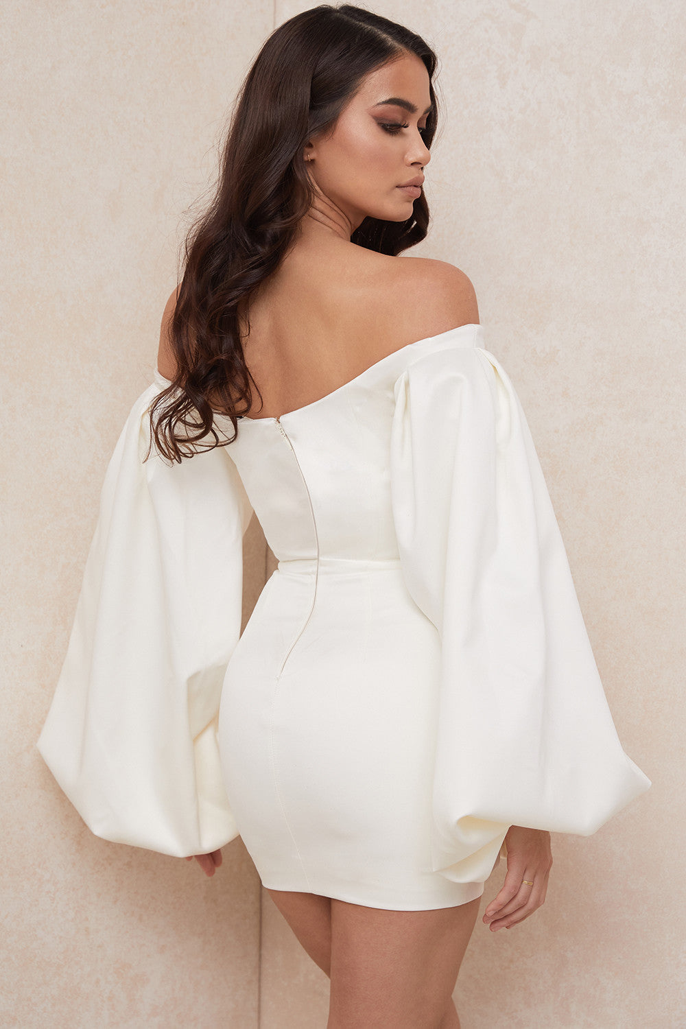 De gladde satijnen stof zorgt voor een luxueuze uitstraling, terwijl de off shoulder snit en dramatische ballonmouwen een vleugje romantiek en allure toevoegen aan je look.