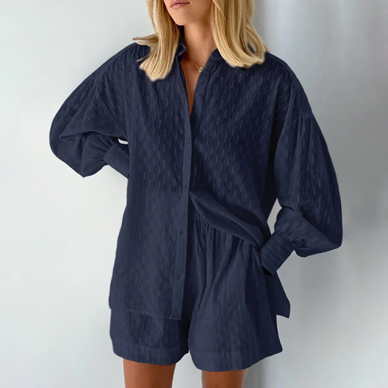 Model draagt tweedelige zomer set voor vrouwen gemaakt van katoen en linnen bestaande uit een blouse met lange mouwen en short met hoge taille losse luchtige top blouse met lantaarnmouwen en oversized fit donkerblauw