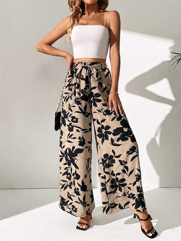 Model draagt wijde broek met bloemenprint en hoge taille losse broek linnen katoenen zomer broek dames met witte top striksluiting taille sluiting beige zwart