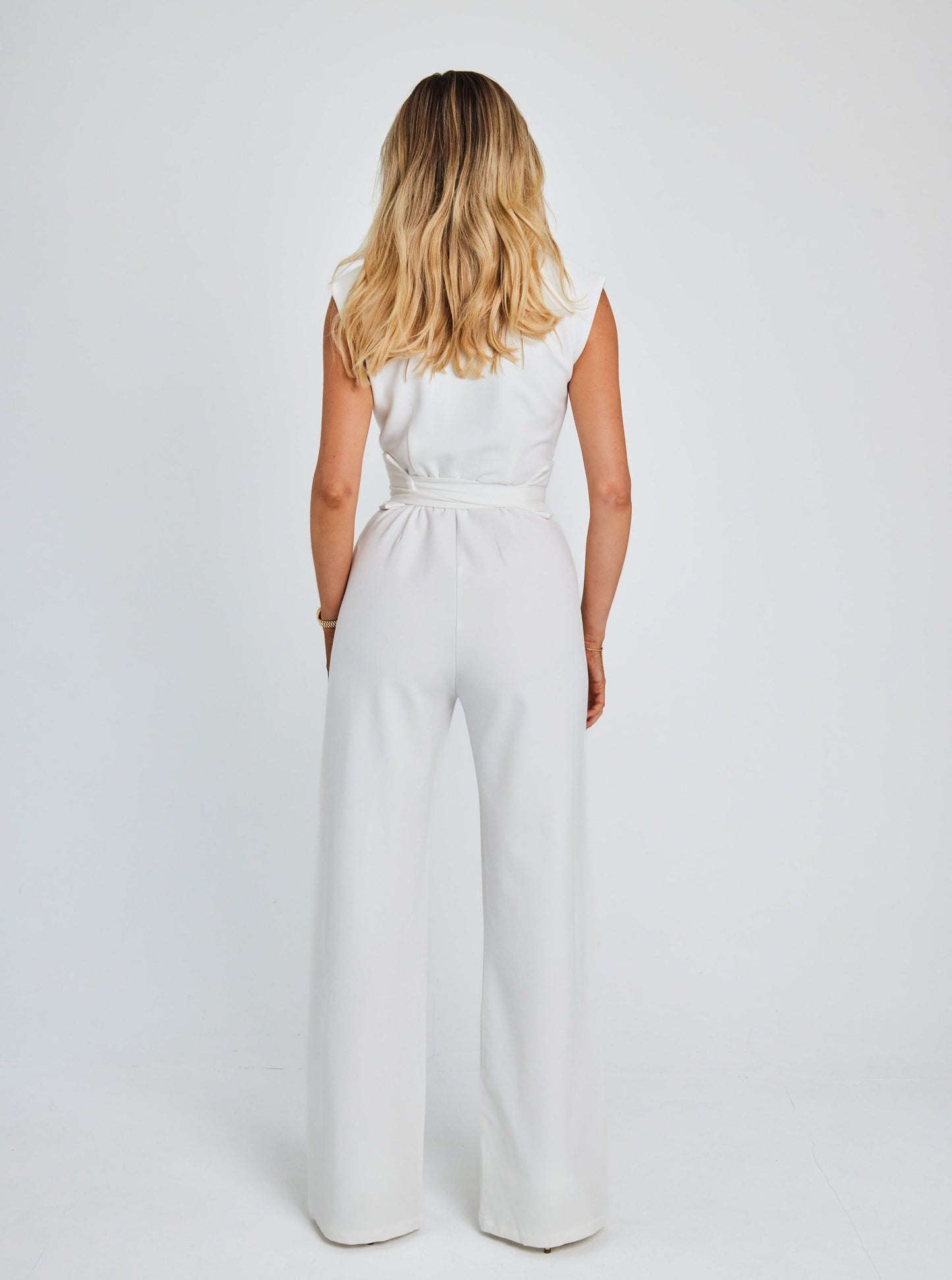 Model draagt Trendy Elegante mouwloze jumpsuit met brede taille band brede riem wijde pijp wit