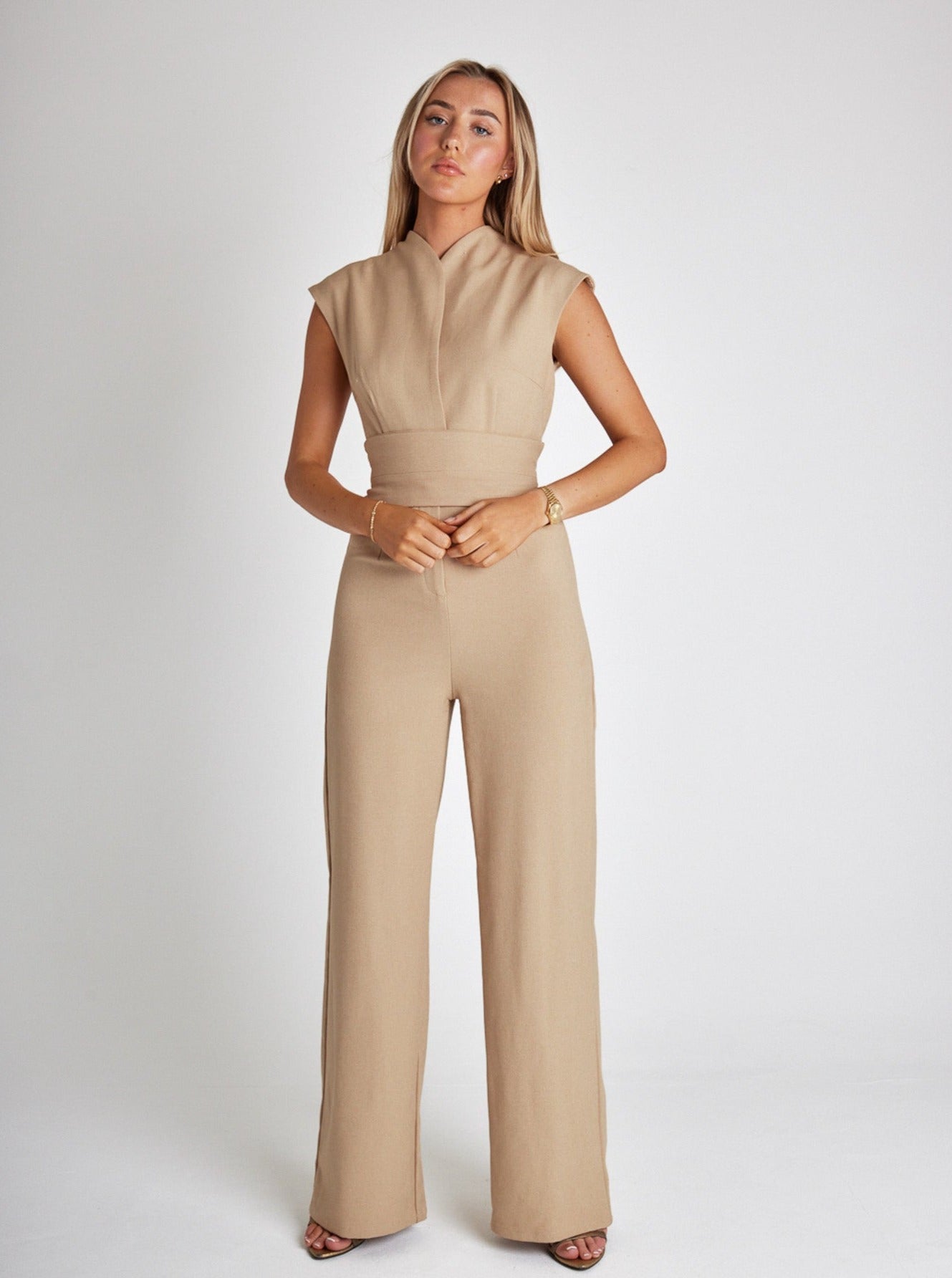 Model draagt Trendy Elegante mouwloze jumpsuit met brede taille band brede riem wijde pijp beige