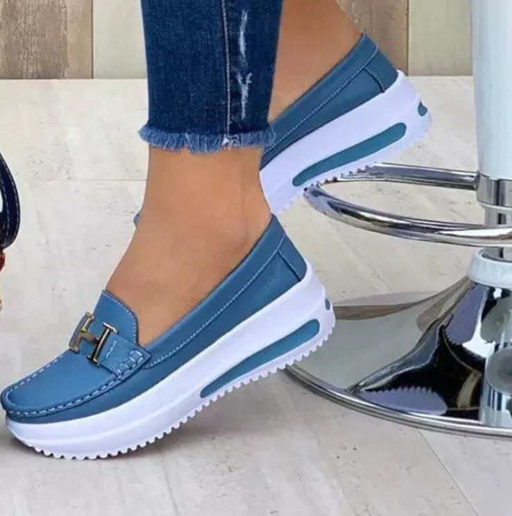 Model draagt Orthopedische loafers sneakers instappers schoenen voor dames met H logo licht blauw