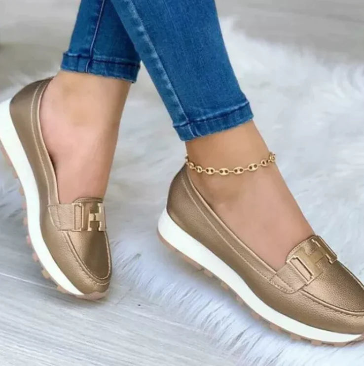 Model draagt Orthopedische loafers sneakers instappers schoenen voor dames met H logo brons