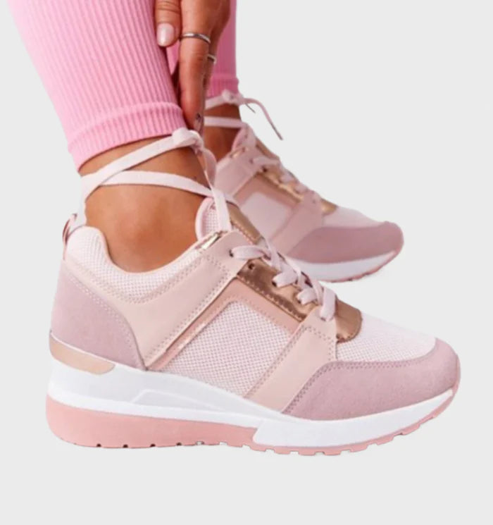 Model draagt orthopedische ondersteunende sneakers met sleehak en veter detail glimmend detail roze